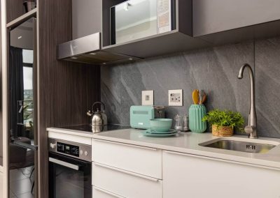 Modern kitchen in Menlyn Maine apartment with stove, microwave, and decor