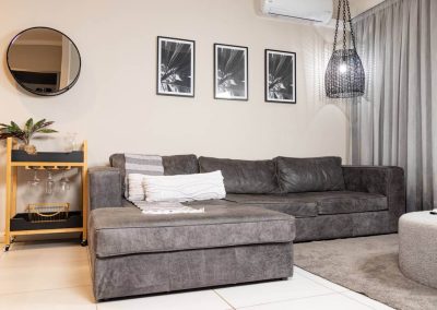 Stylish Menlyn Maine apartment living room with grey sectional sofa and wall art