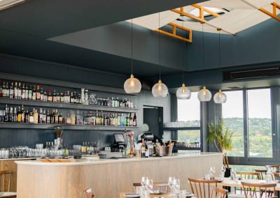 Bar at Menlyn Maine apartment with modern hanging lights, stocked shelves, and panoramic views