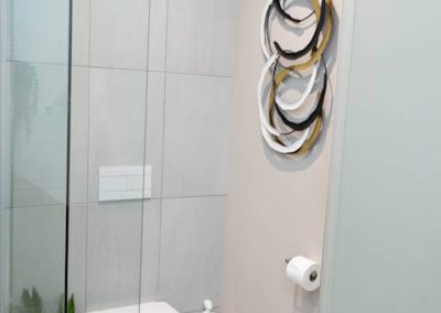 Apartment bathroom at Menlyn Maine featuring modern toilet, glass shower, and wall art