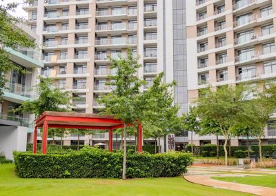Menlyn Maine apartment complex with landscaped garden, trees, and red pergola