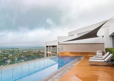 Rooftop swimming pool at Menlyn Maine apartment with deck chairs and scenic views