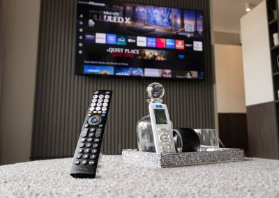 Remote controls on table with TV in Menlyn Maine apartment lounge